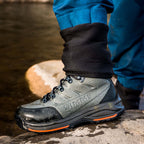 Person wearing a gray Simms MEN's Freestone Wading Boot - Rubber Soles on a rocky surface near water.