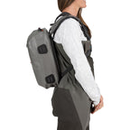 Person wearing a gray backpack and waders on a white background