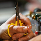 Close-up of hands holding yellow Loon Ergo Precision Tip Scissors with a blurred background