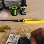 Close-up of fly fishing tools and materials on a wooden surface