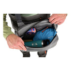 Person opening a gray backpack with items inside on a white background