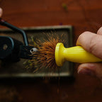 Person using a yellow brush to clean a spiky object with a blurred background