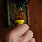 Hand holding a Loon Ergo Hair Packer with bristles against a blurred background