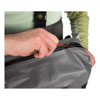 Person zipping a gray bag with a visible brand logo on a white background