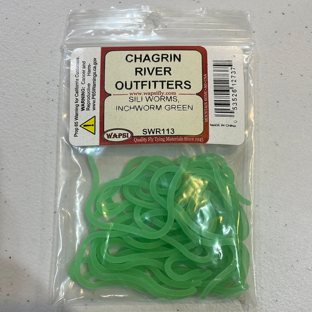 A package of Wapsi Sili Worms, silicone green in color, displayed on a table with the brand label 'Chagrin River Outfitters'.