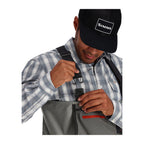 Person wearing Simms Men's Freestone Stockingfoot Waders, featuring gray upper and lower layers with black suspenders and red adjustment straps.