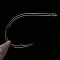 Kona Big Game Hunter (BGH) Fishing hook held in a fly tying vise against a black background