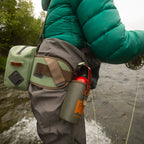 Angler wearing a Fishpond Thunderhead Submersible Lumbar Pack in yucca color