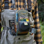 Person wearing a blue vertical chest pack designed for fishing, with a green and brown color scheme, featuring a main compartment zipper, an interior zippered pocket, and attachment loops.