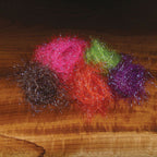 Four colorful Hareline Large Sized UV Polar Chenille bunches on a wooden surface