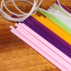 Colorful plastic straws and tubes on a wooden surface
