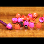 Colorful fishing Hareline Tube Cone Heads on a wooden surface